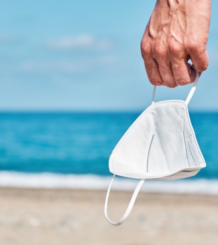 man with a face mask in his hand on the beach