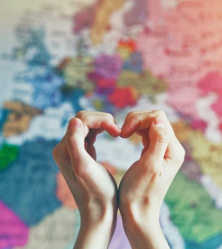 hand in heart shape with love on world map background